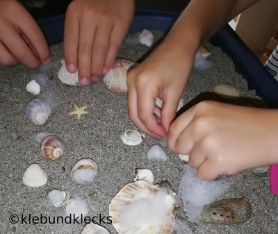 Kinder spielen mit Muscheln