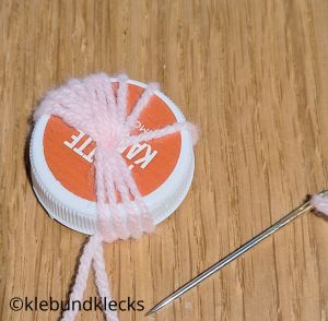 Wolle immer wieder durch Loch fädeln