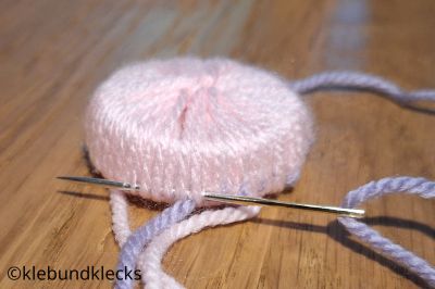 Weitere Wolle durch Wollschlaufen fädeln