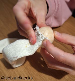 Zwei Kugeln von unterschiedlicher Größe in Strickschlauch stopfen