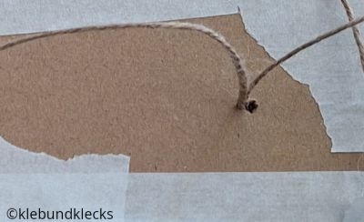 Schnur zum Aufhängen durch Karton fädeln